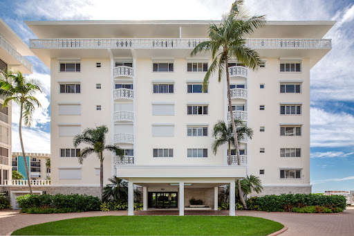 White building with balconies and palm trees in this luxury property for sale in Naples ($1,350,000)