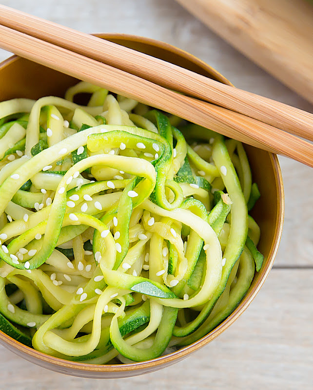 an overhead shot of sesame zucchini noodles in a bowl with chopsticks on the edge