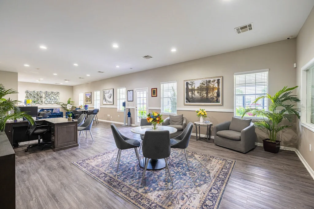 Interior of the clubhouse with multiple seating areas including a bistro table and two arm chairs.