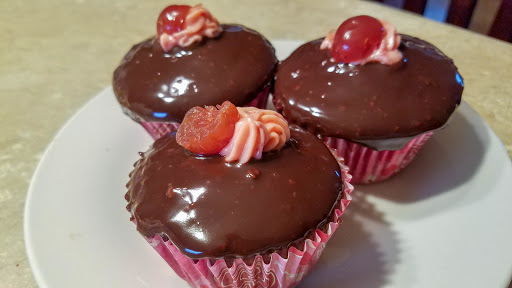 Three chocolate ganache cupcakes on a plate.