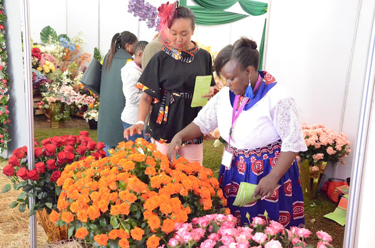 Red Lands sales representative Ann Kingori shows flowers to businesswoman Winnie Williams.