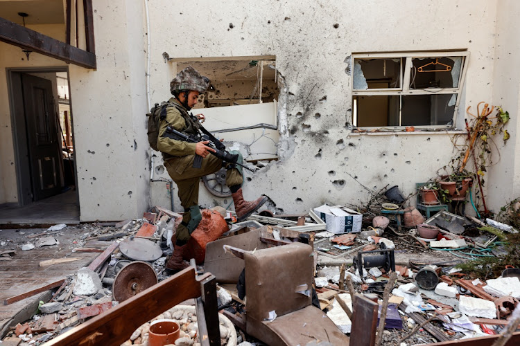 An Israeli soldier steps over personal belongings near a home in in Kibbutz Be'eri in southern Israel after a mass infiltration by Hamas gunmen from the Gaza Strip on October 13 2023.