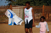 A mother and a child walk past a discarded ballot box at a polling booth in Vuwani, Limpopo. The IEC says 285 parties are expected to contest the national poll. File image