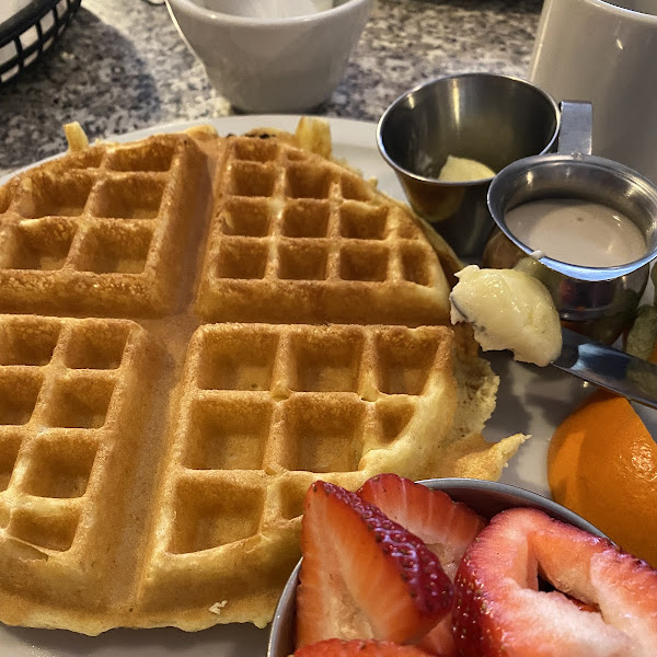 Gluten free Belgium waffle with strawberries and cream cheese syrup.