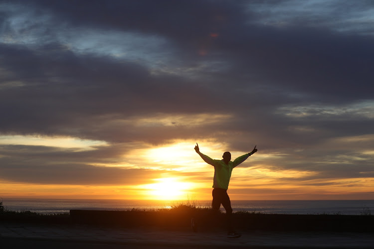 A runner gestures at the camera along the East London Esplanade at sunrise on 1 May. Level 4 lockdown regulations meant the public could exercise outside their homes for the first time in five weeks.