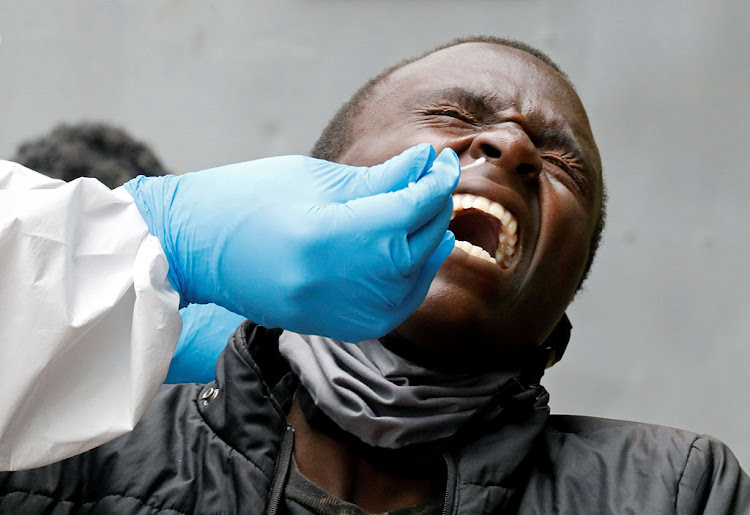 A man reacts as a health worker takes a swab during mass tasting for the coronavirus disease in Kawangware, Nairobi, on May 2, 2020.