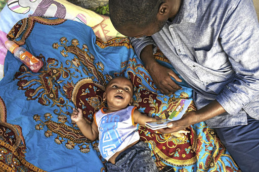 Positive dads raise bright kids. Bulelani Futshane reads a story to little Mario.