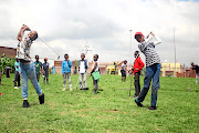 Oratile Pooe and Omphemetse Kolwane swing as they practise golf on a ground which was once a dumping site  in Meadowlands, Soweto. 