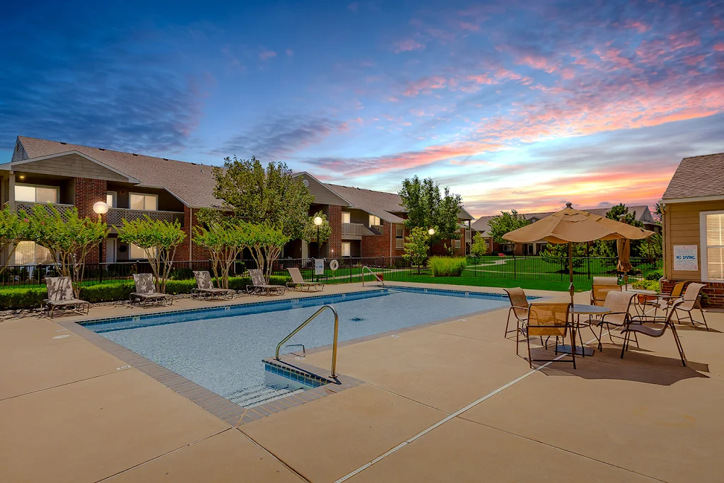 Rosewood Manor apartment swimming pool surrounded by lounge chairs and clubhouse at dusk