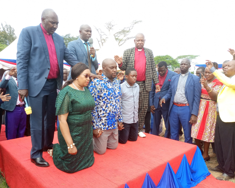 AIC Bishop Joshau Kimuyu and fellow clergymen praying for Kitui Senator Enoch Wambu and his family during a function at Kyondoni Primary school in Kitui West subcounty on Saturday, May 7, 2022.