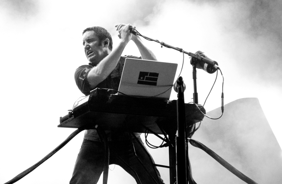 a singer performing on stage with an open laptop next to the microphone stand