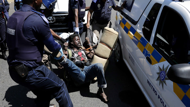 A man belonging to the refugee group in Cape Town is dragged by law enforcement officials on Monday March 2 2020.