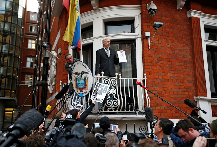WikiLeaks founder Julian Assange holds a copy of a U.N. ruling as he makes a speech from the balcony of the Ecuadorian Embassy, in central London, Britain February 5, 2016.