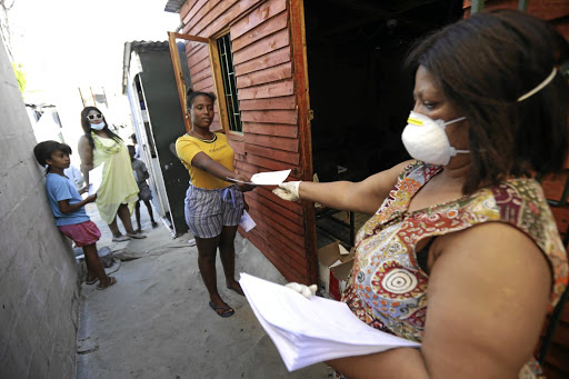 Westlake Primary teacher Elizabeth Koeberg gives pupils schoolwork when they come to pick up their lunch packs.