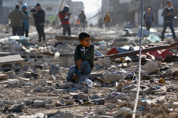 A Palestinian child sits among the rubble of houses destroyed in an Israeli strike during the conflict. Picture: IBRAHEEM ABU MUSTAFA