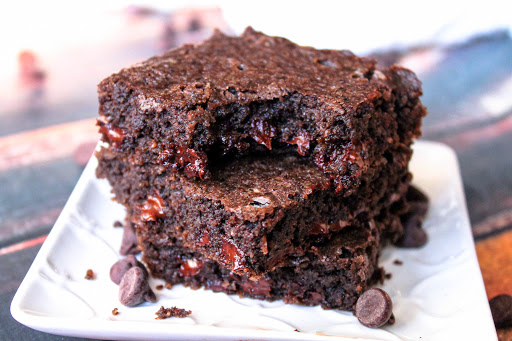 A stack of Fudgy Keto Brownies with a bite taken out of one brownie.