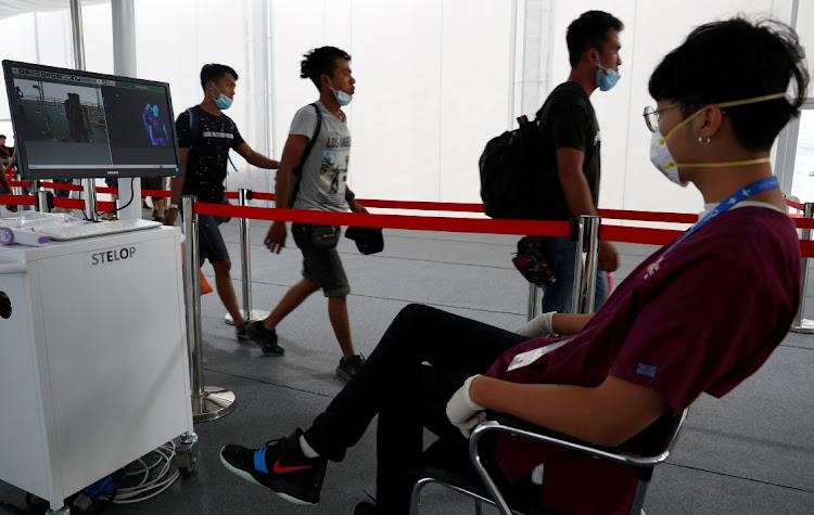 Contractors and workers pass a thermal scanner as part of the coronavirus outbreak precautions during a media preview of the Singapore Airshow in Singapore February 9, 2020.