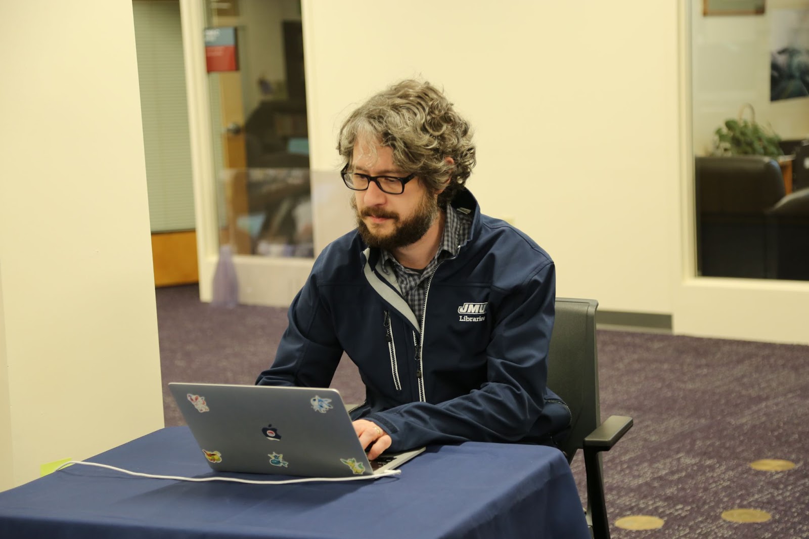 photo of Brian Sullivan, who is wearing a JMU Libraries jacket and thick rimmed glasses and has a beard