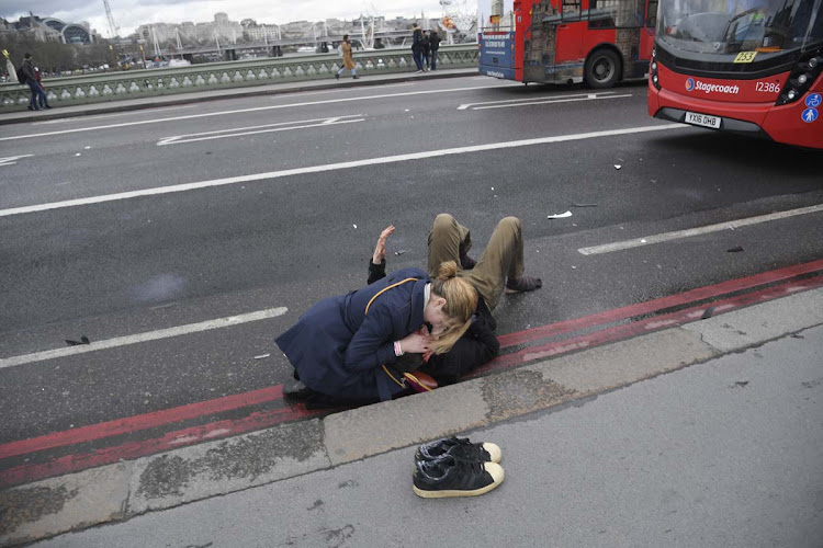 A woman assists an injured person after an attack on Westminster Bridge in London, March 22, 2017. Four people were killed when 52-year-old Khalid Masood drove a car into pedestrians on the pavement.