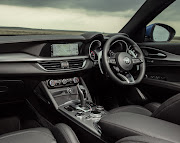 The dashboard apes the same driver-centric fascia layout as the Giulia, with a slim three-spoke steering wheel integrating the ignition button, flanked by two cold shifter paddles.