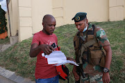 A SANDF officer checks the permits of an essential worker 