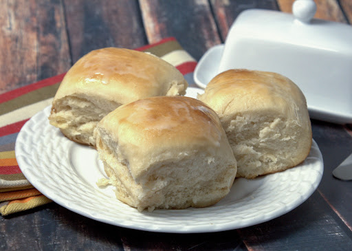 Three old-fashioned soft and buttery yeast rolls on a plate.