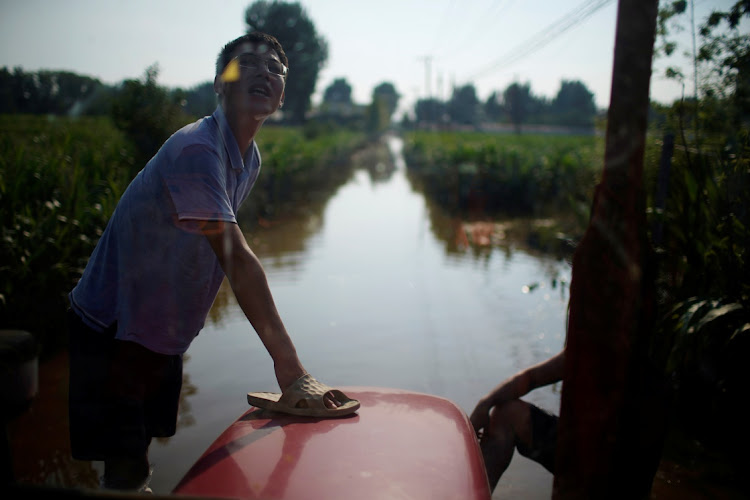 A man stands on a vehicle in a flooded farmland following heavy rainfall in Wangfan village of Xinxiang, Henan province, China, on July 25 2021. Picture: REUTERS/ALY SONG