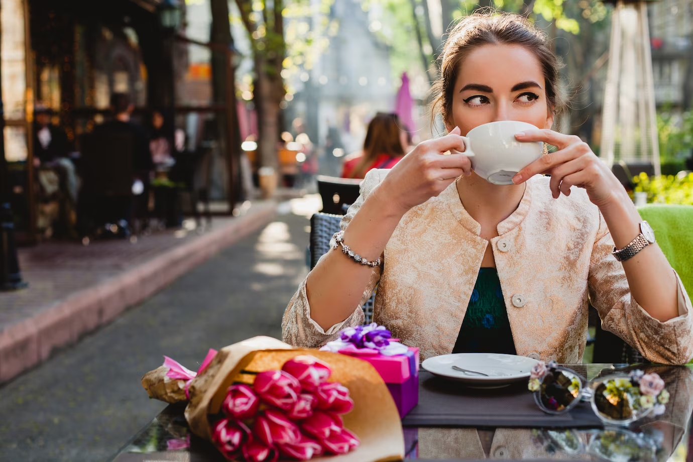 Young stylish woman sitting in cafe, holding cup of cappuccino