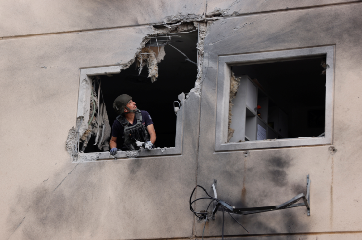 An Israeli police bomb disposal expert looks out from the window of a residential building that was damaged after it was hit by a rocket launched from the Gaza Strip, in Ashkelon, southern Israel on May 11 2021.