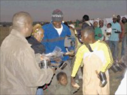 DARK VELD: Foreigners receive their rations for the night at a refugee camp in Olifansfontein, Midrand. Pic. Bafan Mahlangu. 01/06/2008. © Sowetan.