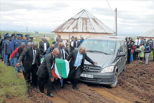 SAD FAREWELL: Police members hoist a coffin bearing the body of slain senior Hawks investigator Warrant Officer Dalibandla Qokoyi, who was laid to rest in Mthozela village in Qumbu over the weekend Picture: SIKHO NTSHOBANE