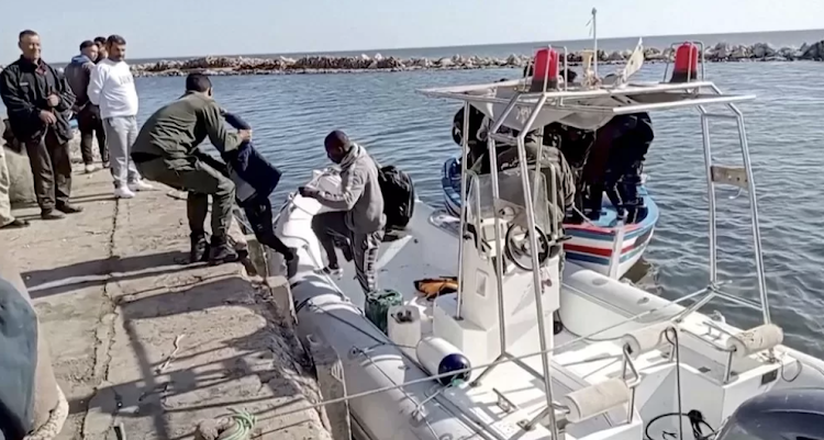 A Tunisian national coast guard helps a child to get off a rescue boat back in April