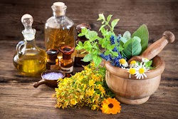 Essential oil, mortar with fresh herbs and bath salt on wooden background