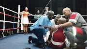 Doctor Solly Skosana, trainer Stanley Ndlovu and a paramedic attend to stricken boxer Phindile Mwelase before rushing her to hospital. She was caught by a right-handed punch to the head during a bout in Pretoria. Her opponent, Liz Butler, is in her corner