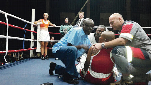 Doctor Solly Skosana, trainer Stanley Ndlovu and a paramedic attend to stricken boxer Phindile Mwelase before rushing her to hospital. She was caught by a right-handed punch to the head during a bout in Pretoria. Her opponent, Liz Butler, is in her corner