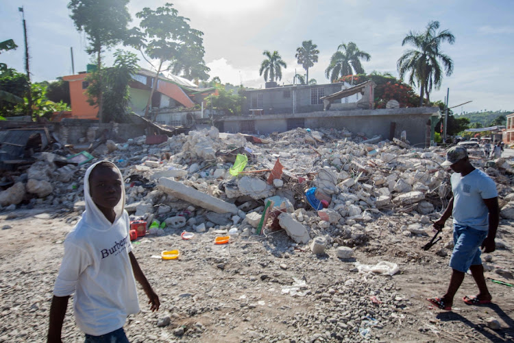 Men walk among the debris of a collapsed building after a 7.2-magnitude earthquake struck Haiti on August 16, 2021 in Corvalion, Les Cayes, Haiti. Picture; GETTY IMAGES/RICHARD PIERRIN