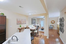 Open concept kitchen, dining, and living area with wood-inspired flooring, neutral walls, and white trim throughout 