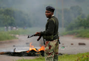 A soldier stands before a burning barricade during protests in Harare, Zimbabwe. SA is treating Emmerson Mnangagwa exactly as it used to treat Robert Mugabe: with sickening, immoral deference. 