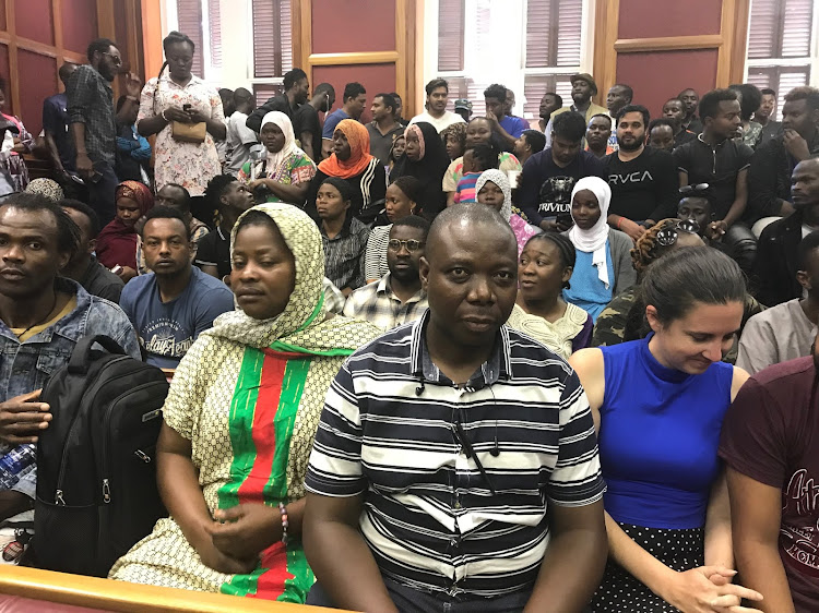 Refugees who have been living at the Central Methodist Mission on Greenmarket Square at the Cape Town High Court on Friday. Wearing stripes is their leader, Jean-Pierre Balous.