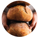 Hands holding three loaves of sourdough in a stack.