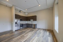 Kitchen with stainless steel appliances, wood cabinets, white stone countertops, and tile backsplash