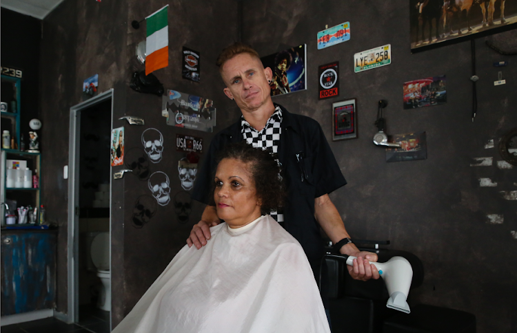 Chris Weineke from Barker Barber Shop in Newton Park is losing business due to certain services like blow drying cant be done during blackouts . On the left is one of his clients, Michelle Serfontein .