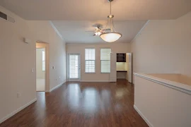 Dining area with an overhead light, tan walls, wood-inspired flooring, and adjacent to the living area