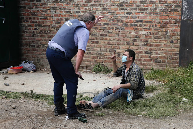 A police member talks to a shop worker after his store in Timothy Valley was looted on the April 14. Several arrests were made by the police