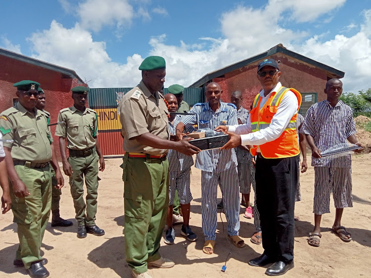 Water For Life Director Awadh Abdalla hands over computers to officials and inmates at the Hindi GK Prison in Lamu.