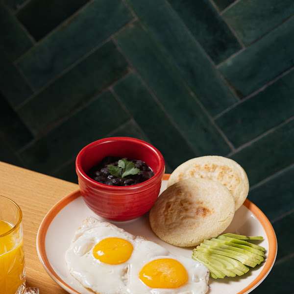 Venezuelan breakfast that includes Arepas, black beans, fried eggs and avocado.