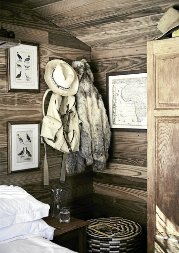 The bedroom is filled with campaign-style pieces and decor touches, such as ornithological drawings and maps.