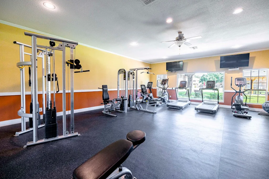 Modern gym inside an apartment complex with various exercise machines and bright lighting.