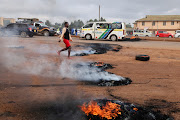 A woman walks past burning tires during clashes that erupted after a Kenyan police officer shot dead several people and himself in a rampage attack in Nairobi, Kenya, December 7, 2021. 