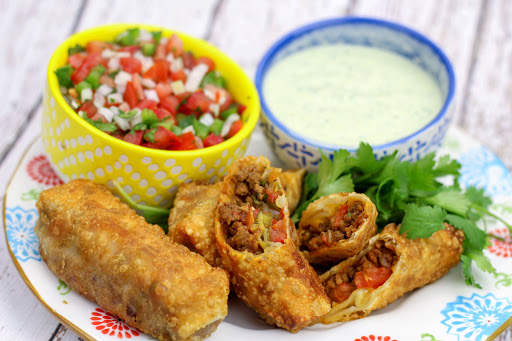 Taco egg rolls with cilantro dipping sauce and pico de gallo.